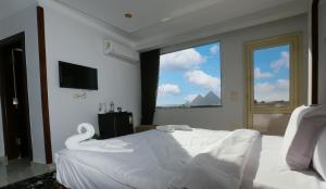 a bedroom with a large white bed with a large window at NEW ASSER HOTEL PYRAMID in Cairo