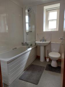 a bathroom with a tub and a toilet and a sink at Stunning seaside town cottage in Cardigan