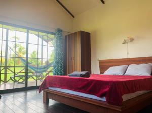 um quarto com uma cama com um cobertor vermelho e uma varanda em Plantage Resort Frederiksdorp em Paramaribo