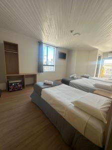 una camera d'albergo con due letti e una finestra di Unity Hotel - Votorantim - SP a Votorantim