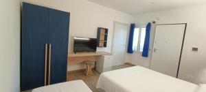a bedroom with two beds and a desk with a television at Agriturismo Sa Pramma in Santa Maria la Palma