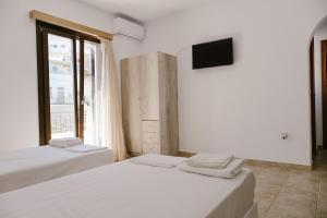two beds in a room with a tv and a window at Iliachtida apartments in Philotium