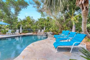a group of blue lounge chairs next to a swimming pool at Roosevelt Cottage in Captiva