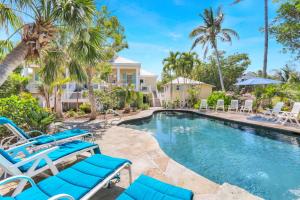 a swimming pool with blue chairs and palm trees at Roosevelt Cottage in Captiva