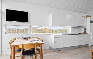 Una cocina con gabinetes blancos y una mesa con sillas. en Awesome Home In Hejls, en Hejls