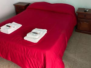 ein Bett mit roter Bettwäsche und Handtüchern darauf in der Unterkunft Hotel Sol in Termas de Río Hondo