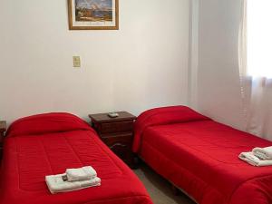 2 Betten in einem Zimmer mit roter Bettwäsche und Handtüchern in der Unterkunft Hotel Sol in Termas de Río Hondo