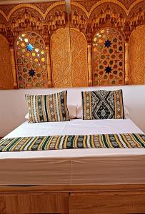 Bett mit einem Kopfteil aus Holz und Kissen darauf in der Unterkunft SULTANA Beach Riad in Saidia 