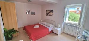 Un pequeño dormitorio con una cama roja y una ventana en Apartments & Rooms Nada, en Brseč
