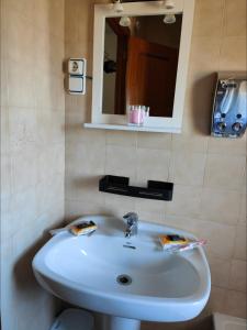 La salle de bains est pourvue d'un lavabo blanc et d'un miroir. dans l'établissement vilaboa - servicio de habitaciones, à Bóveda