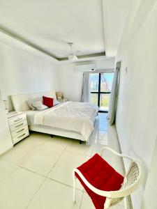 um quarto com uma cama e uma cadeira vermelha em Flat Mar Montanha Four Seasons no Rio de Janeiro