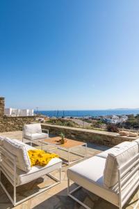 a group of lounge chairs and tables on a roof at Villa Cabana by EneaTinos - 3BR SeaView in Tinos Town