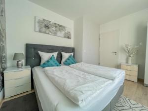 1 dormitorio con 1 cama blanca grande con almohadas azules en Relax Prémium Wellness Apartman, en Siófok