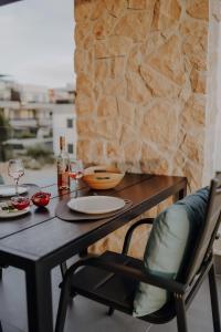 una mesa y una silla con copas de vino y una pared de piedra en Lili Rose Mandre Luxury Apartments, en Mandre