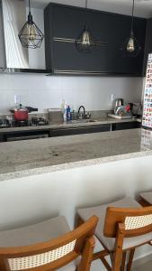 een keuken met zwarte kasten en 2 stoelen en een tafel bij Bella House in Luis Eduardo Magalhaes