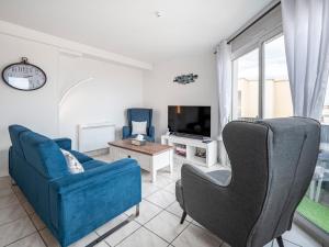 a living room with a blue couch and a tv at T3 Vue Mer Clim Wifi Parking in Canet-en-Roussillon