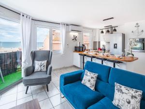 a living room with a blue couch and a kitchen at T3 Vue Mer Clim Wifi Parking in Canet-en-Roussillon