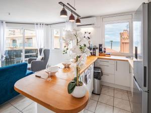 a kitchen with a table with a vase of flowers on it at T3 Vue Mer Clim Wifi Parking in Canet-en-Roussillon