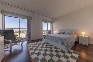a bedroom with a bed and a chair and windows at Xenon Urban Apartments in Maputo