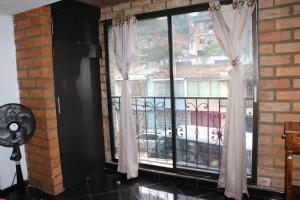 Zimmer mit einem Fenster mit Vorhängen und einem Ventilator in der Unterkunft Aparta Suite Torre De Prado 301 in Medellín