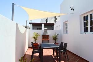 a patio with a table and chairs on a white wall at Mirafondo Beach in Playa Honda