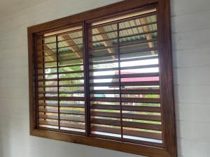 a window with wooden shutters on a wall at Dolphin Blue Paradise in Bocas del Toro