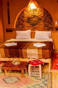 a bed in a room with a brick wall at Auberge Kasbah Dar Sahara Tours in Mhamid