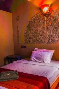 a bedroom with a bed with a rock wall at Auberge Kasbah Dar Sahara Tours in Mhamid