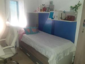 a small bedroom with a bed and a chair at Casa Adosada in Bormujos
