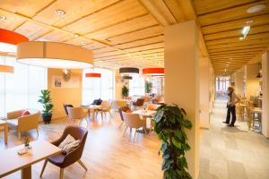a restaurant with tables and chairs and a person in the background at JUFA Hotel Annaberg in Annaberg