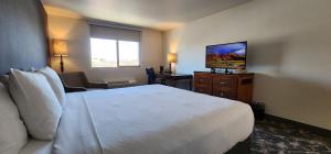 Habitación de hotel con cama blanca y silla en The Dalles Inn en The Dalles