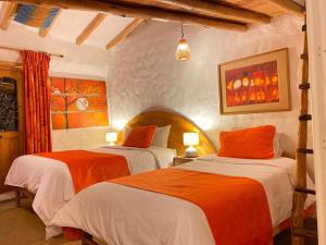 1 dormitorio con 2 camas con sábanas de color naranja y blanco en Hostal Madre Tierra en Cusco