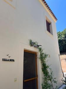 a white building with a door and plants on it at Villa Nova s.r Sea View in Porto Heli