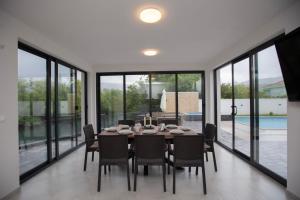 a dining room with a table and chairs and windows at Villa H in Blagaj