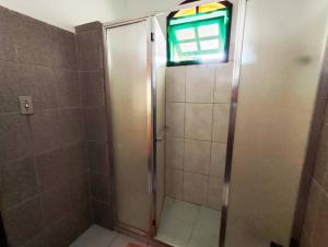 una doccia con porta in vetro e finestra di Suites Americanas Em Jaconé a Jaconé