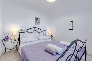 a white bedroom with a large bed with two tables at Corcyra Nigra Apartment 2 in Blato