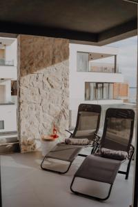 two chairs in a room with a stone wall at Lili Rose Mandre Luxury Apartments in Mandre