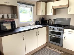 a kitchen with white cabinets and a sink and a microwave at Chalet Between Ostend and Bruges in Jabbeke
