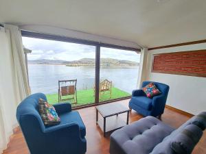 - un salon avec deux chaises bleues et une grande fenêtre dans l'établissement Uros Aruma-Uro on Uros Floating Islands, à Puno