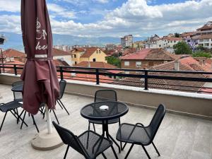 um pátio com uma mesa, cadeiras e um guarda-sol em Ora Apartament em Pogradec