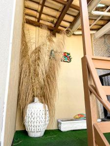 a vase filled with dry grass sitting next to a wall at Casa Solar Sansoan in Arraial do Cabo +42 photos