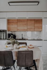 una mesa de comedor con sillas y una cocina blanca en Lili Rose Mandre Luxury Apartments en Mandre