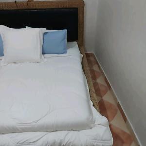 a bed with white sheets and blue pillows at Cozy in Midelt - Downtown apartment in Midelt