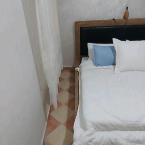 a bedroom with a bed with white sheets and blue pillows at Cozy in Midelt - Downtown apartment in Midelt