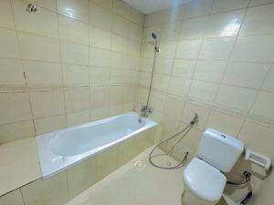 a bathroom with a toilet and a bath tub at Modern Comfort Fully Furnished Room for Rent in Ajman  +21 photos