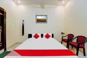 una camera da letto con un letto con cuscini rossi e due sedie di OYO Flagship Hotel Centre Point a Chupra