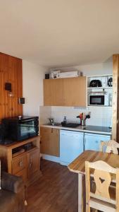 appartement parc aux etoiles في بوي-سانت-فينسينت: مطبخ مع الاجهزة الزرقاء وطاولة في الغرفة