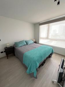 a bedroom with a bed with a green blanket on it at Laguna del Mar, Playa Arrecife in La Serena