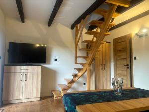 a room with a wooden table with a television and stairs at Domek Sosnowe Wzgórze Wiktorowo in Gąsawa