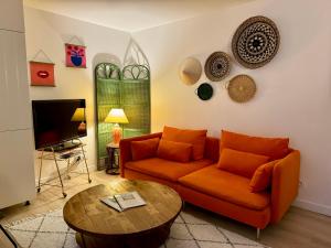 a living room with an orange couch and a table at Au Canon - Parking gratuit - Bords de Loire in Orléans
